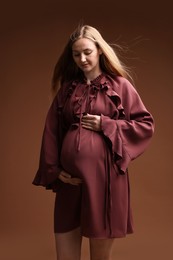 Photo of Beautiful pregnant woman in dress on brown background