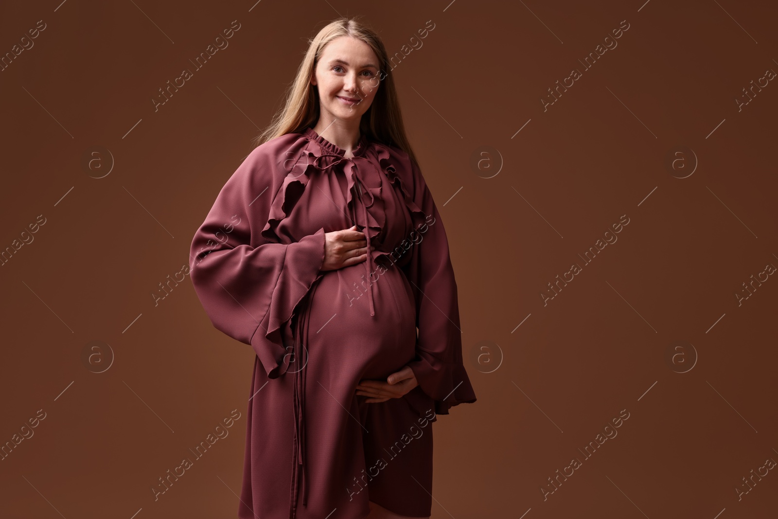 Beautiful pregnant woman in dress on brown background Photo of Beautiful pregnant woman in dress on brown background