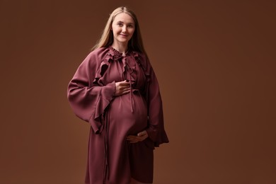 Photo of Beautiful pregnant woman in dress on brown background