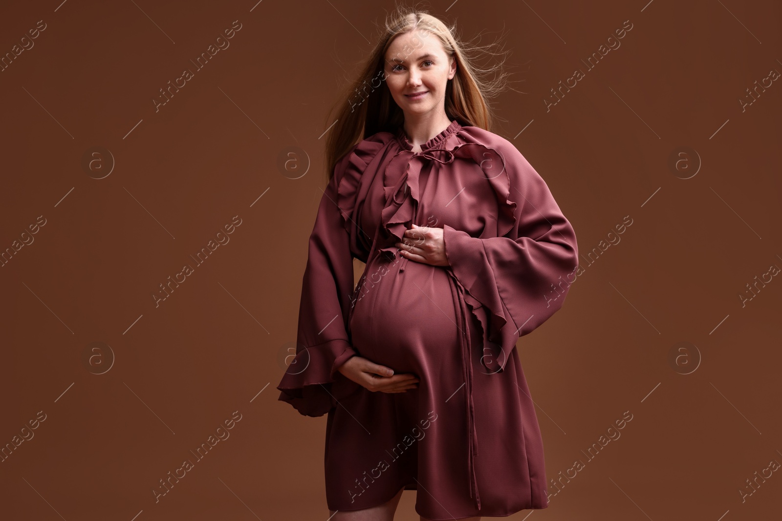 Beautiful pregnant woman in dress on brown background Photo of Beautiful pregnant woman in dress on brown background