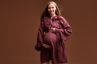Photo of Beautiful pregnant woman in dress on brown background