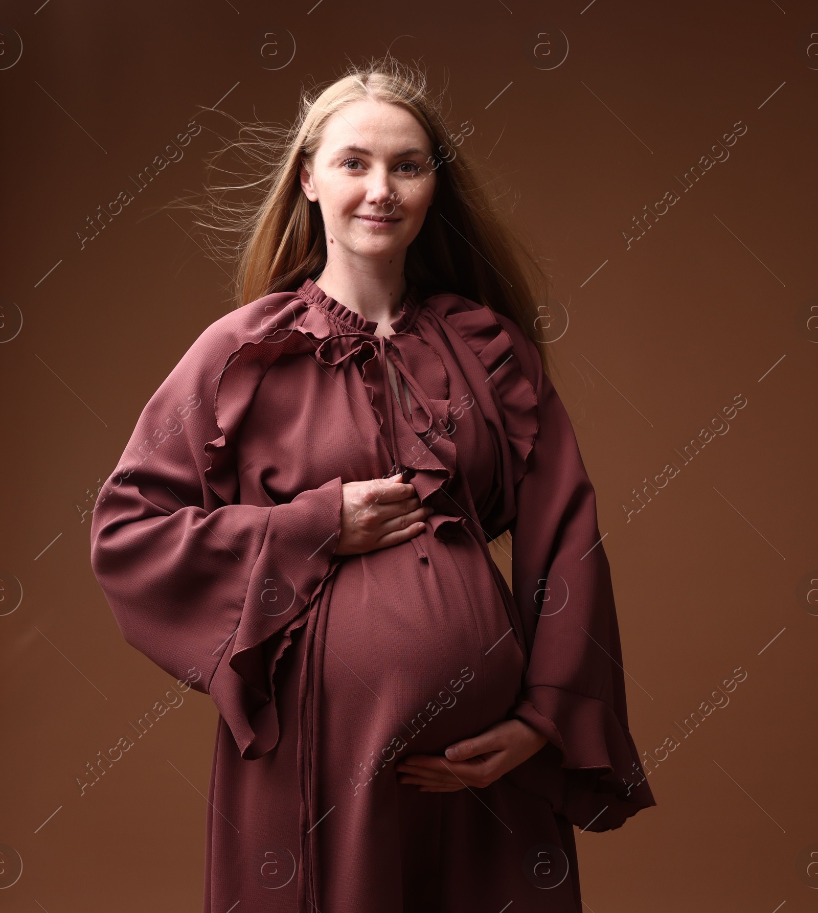 Beautiful pregnant woman in dress on brown background Photo of Beautiful pregnant woman in dress on brown background