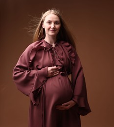 Photo of Beautiful pregnant woman in dress on brown background