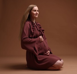Photo of Beautiful pregnant woman in dress on brown background
