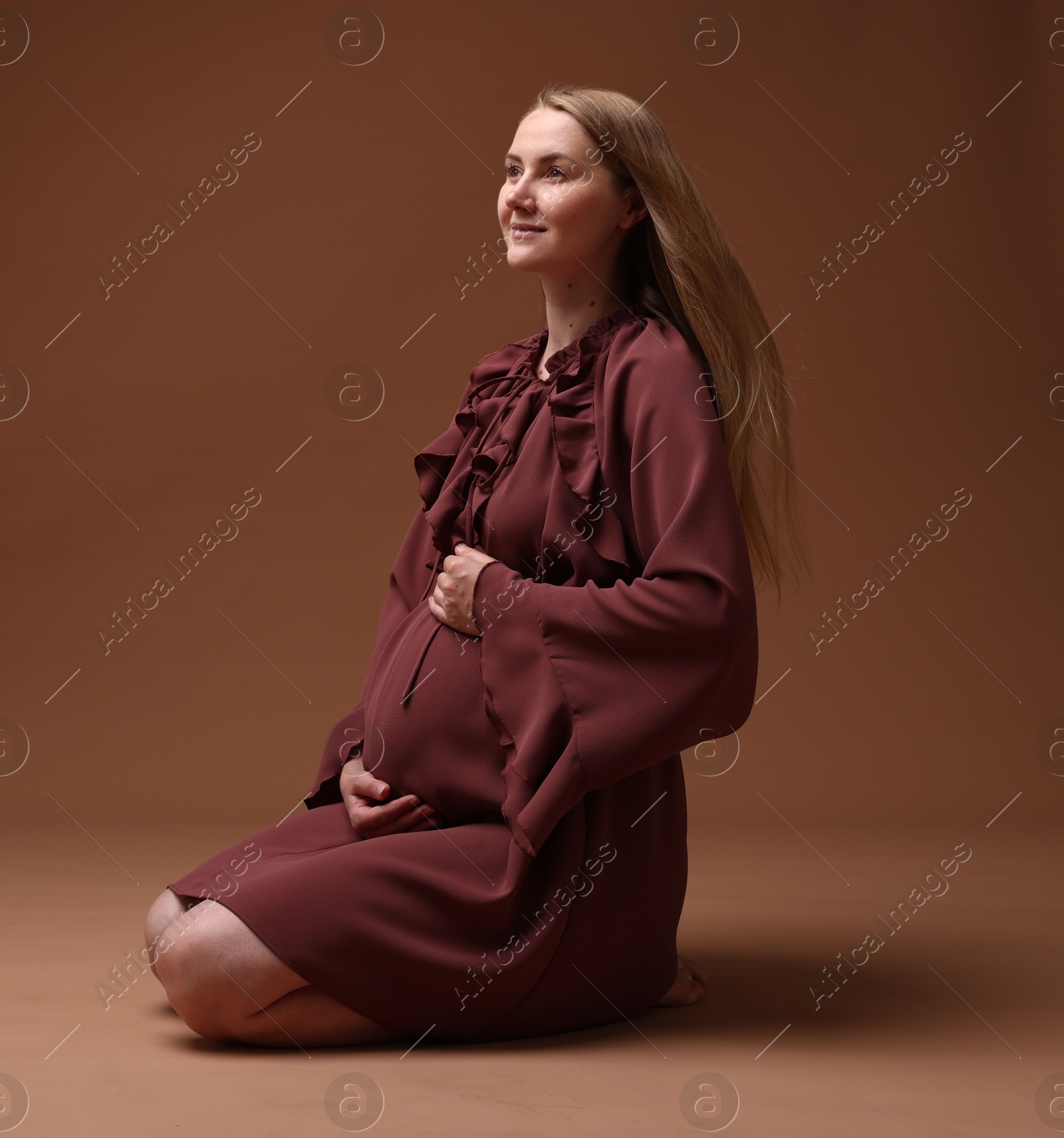 Beautiful pregnant woman in dress on brown background Photo of Beautiful pregnant woman in dress on brown background