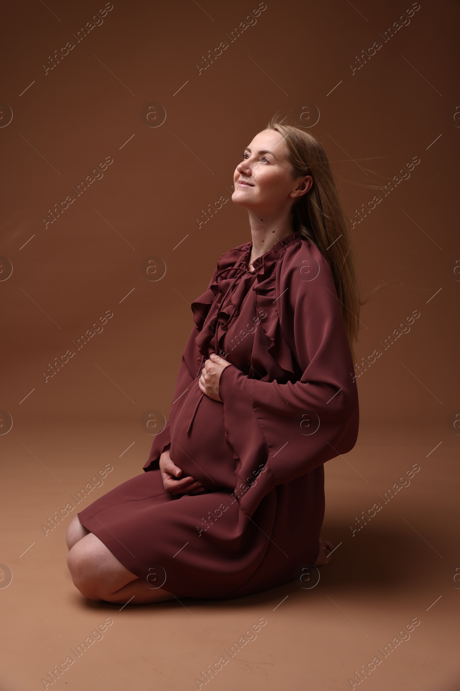 Beautiful pregnant woman in dress on brown background Photo of Beautiful pregnant woman in dress on brown background