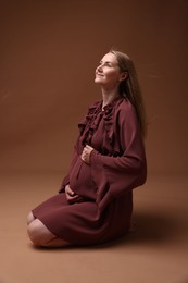 Photo of Beautiful pregnant woman in dress on brown background
