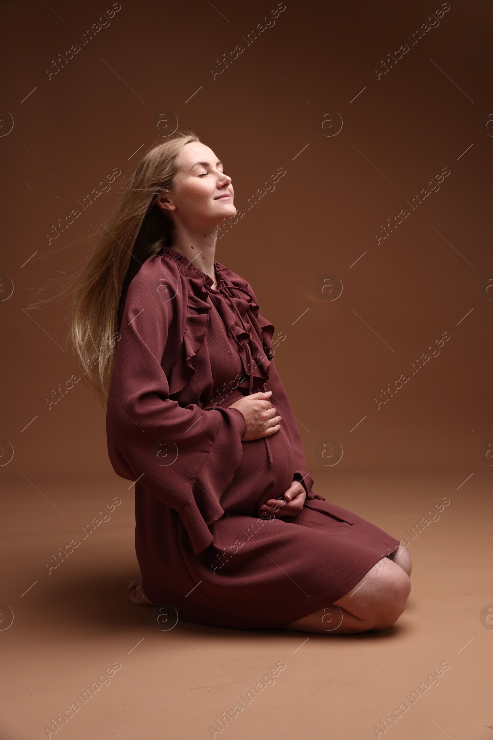 Beautiful pregnant woman in dress on brown background Photo of Beautiful pregnant woman in dress on brown background