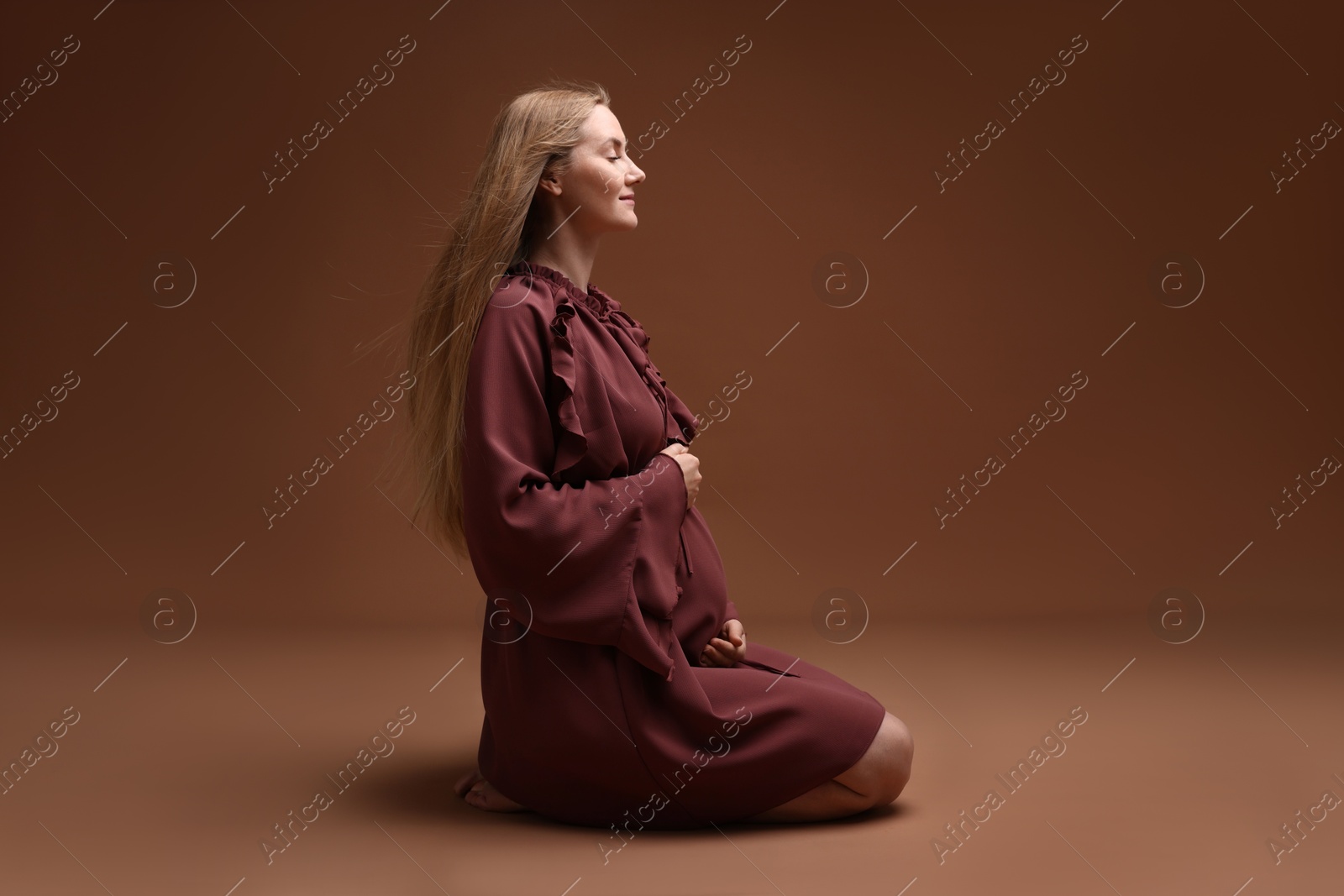 Beautiful pregnant woman in dress on brown background Photo of Beautiful pregnant woman in dress on brown background