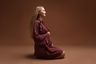Photo of Beautiful pregnant woman in dress on brown background