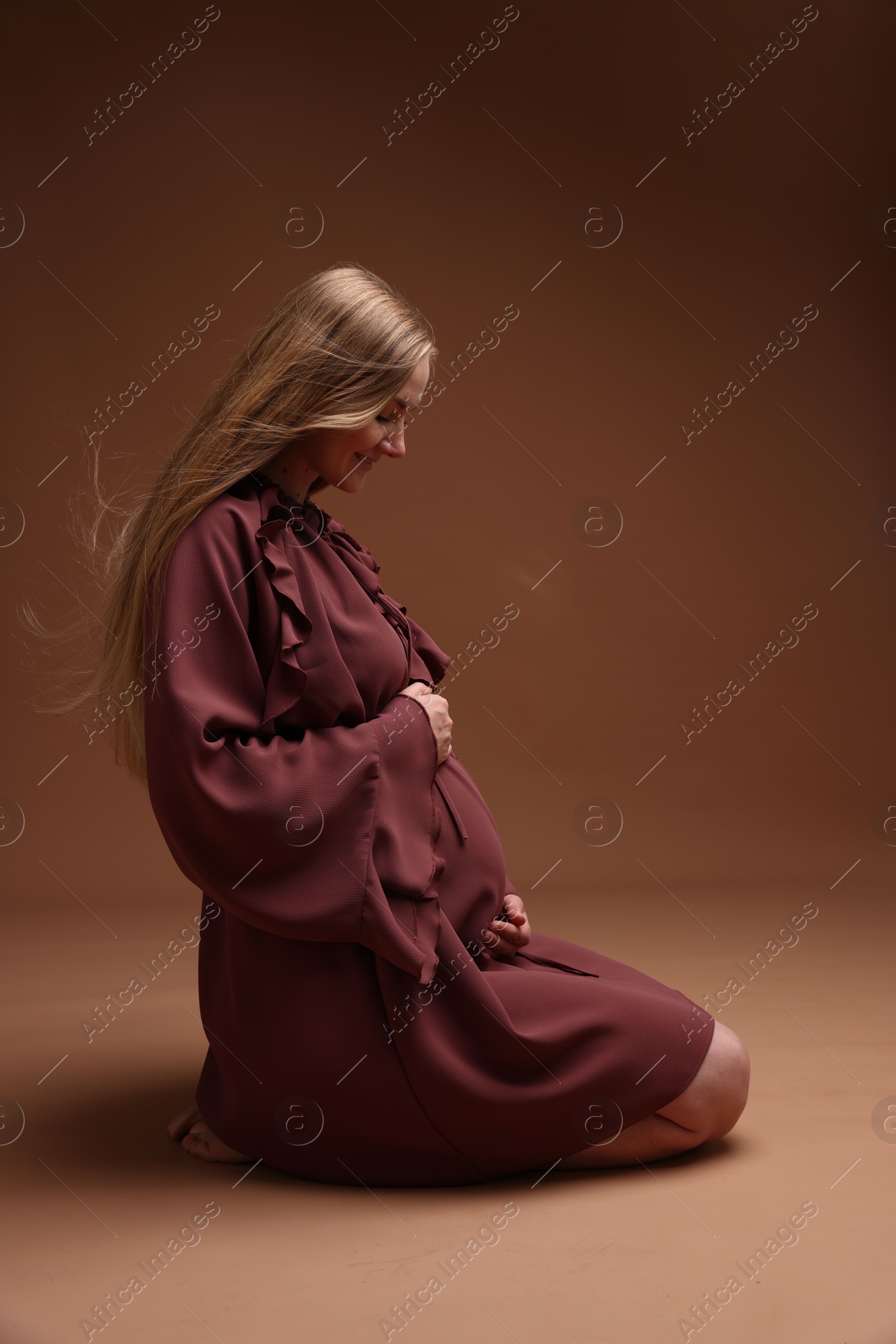 Beautiful pregnant woman in dress on brown background Photo of Beautiful pregnant woman in dress on brown background
