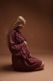 Photo of Beautiful pregnant woman in dress on brown background