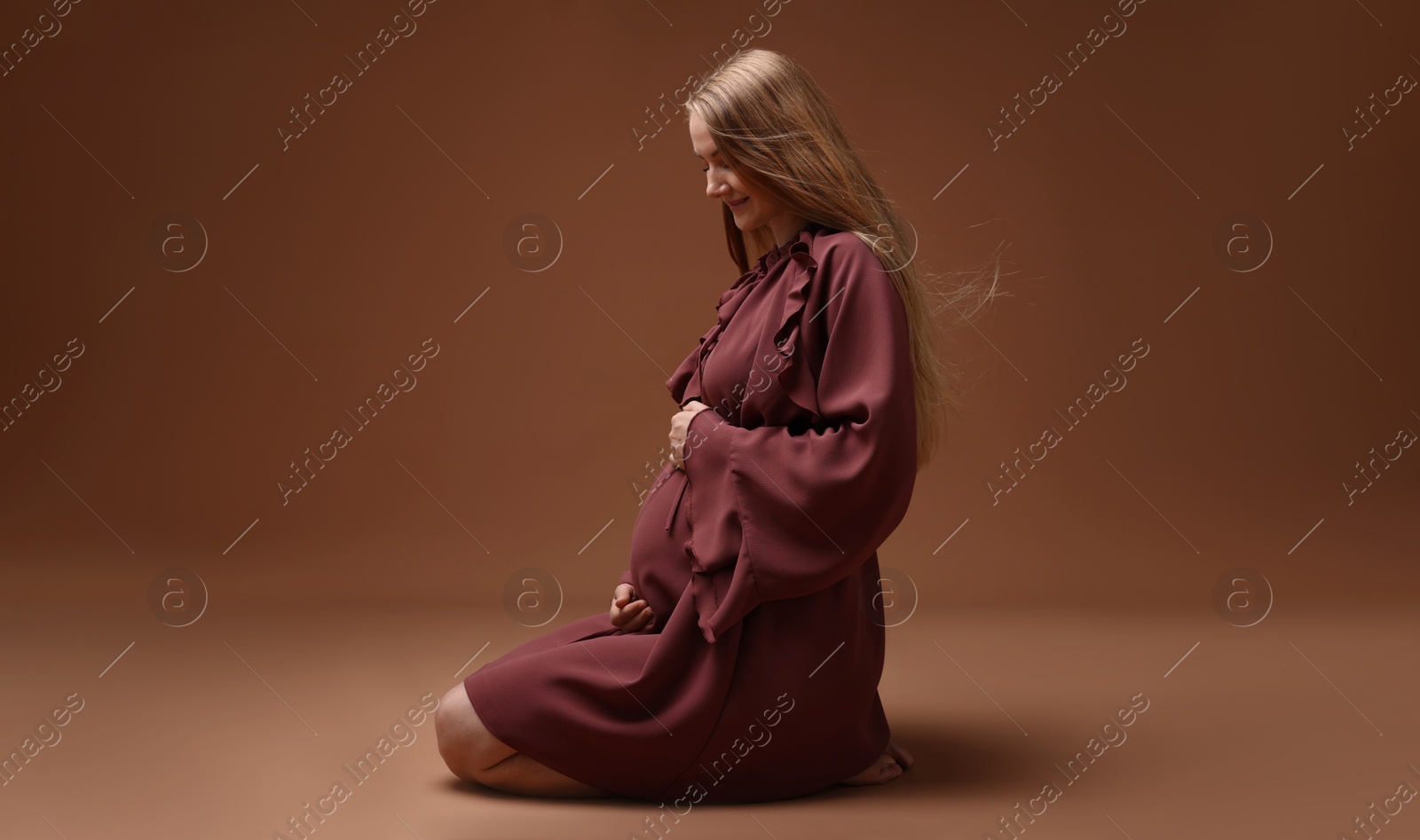 Beautiful pregnant woman in dress on brown background Photo of Beautiful pregnant woman in dress on brown background