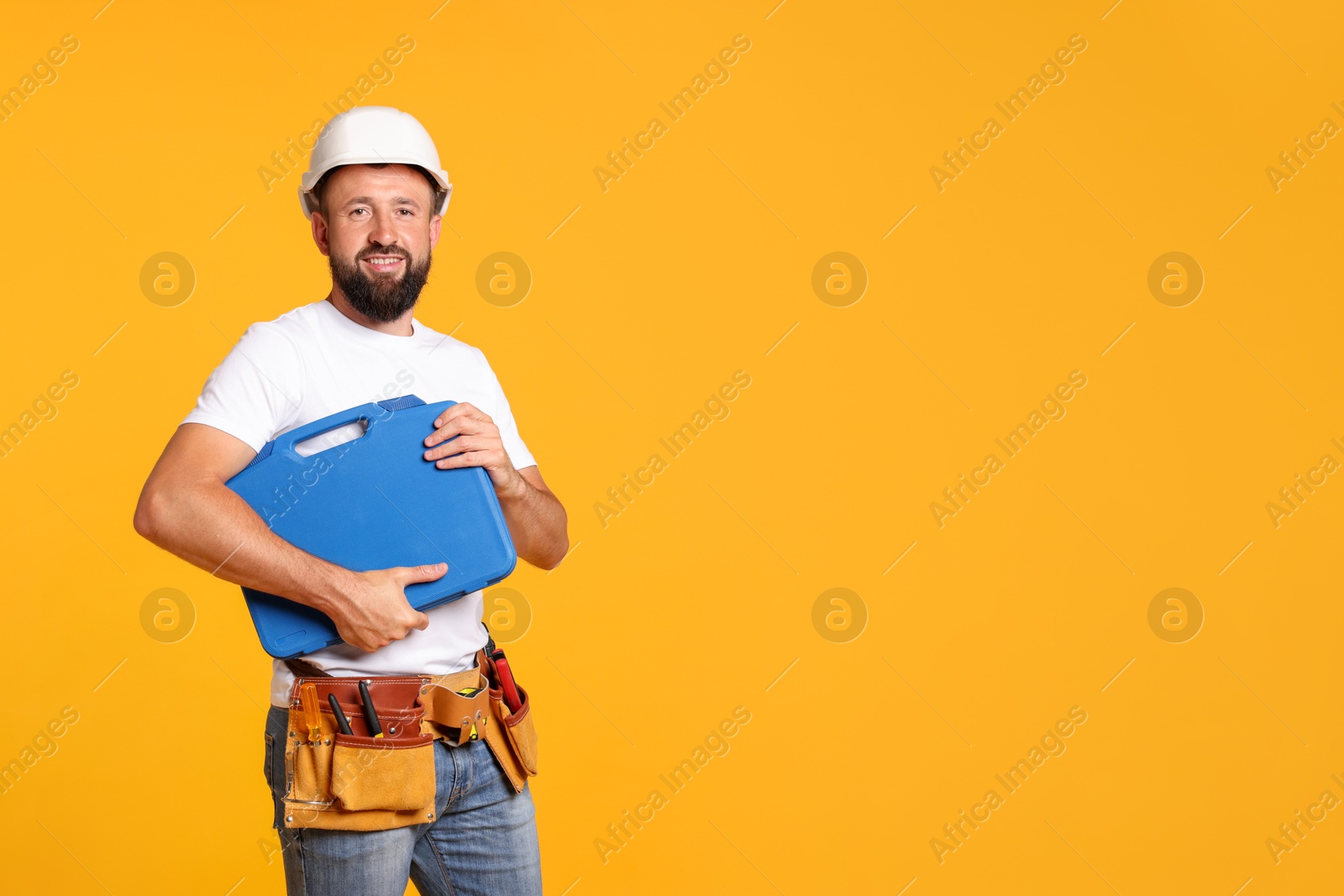 Professional repairman with tool box on orange background, space for text Photo of Professional repairman with tool box on orange background, space for text