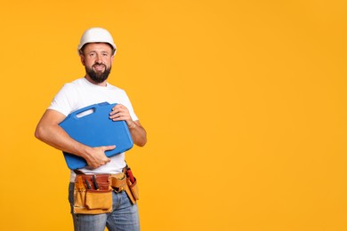 Photo of Professional repairman with tool box on orange background, space for text