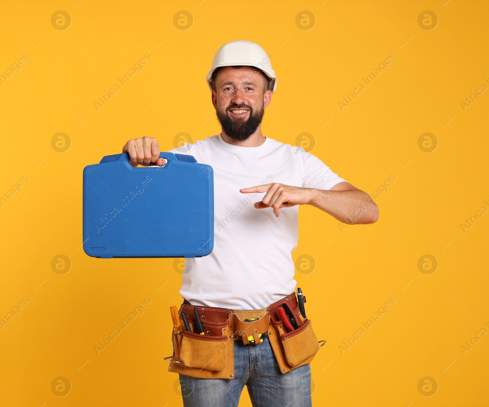 Professional repairman with tool box on orange background Photo of Professional repairman with tool box on orange background