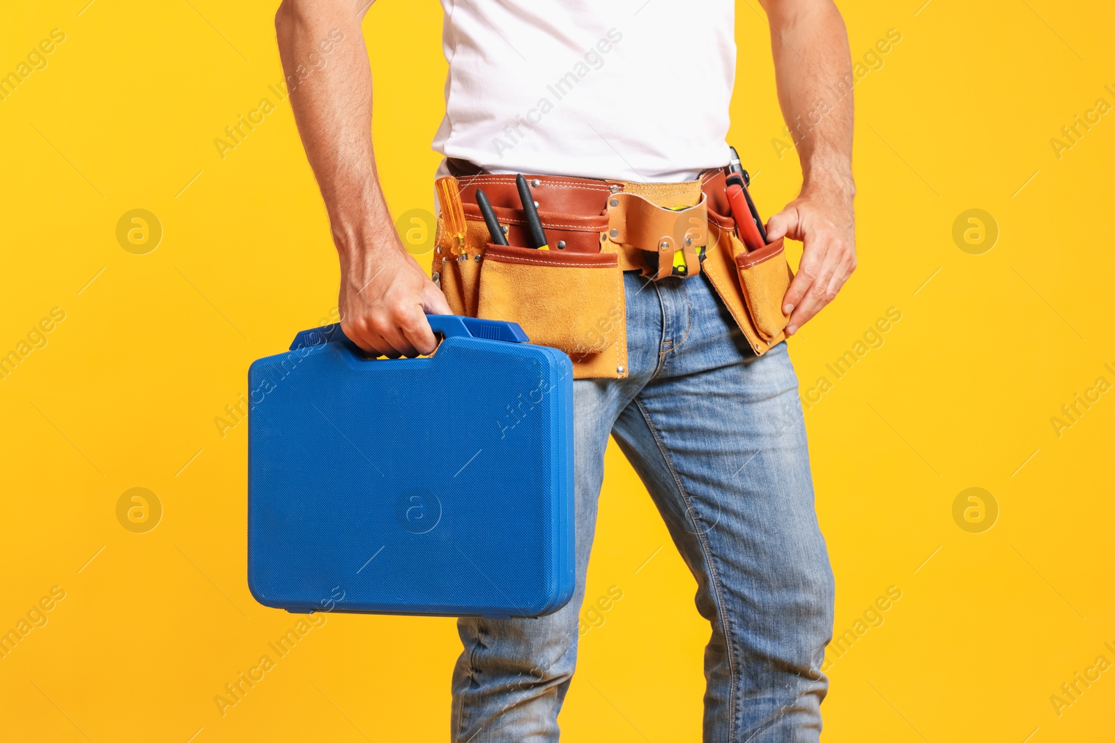 Professional repairman with tool box on orange background, closeup Photo of Professional repairman with tool box on orange background, closeup
