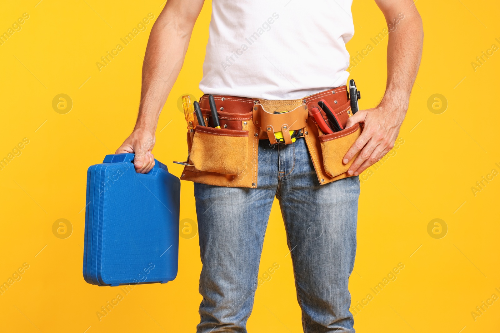 Professional repairman with tool box on orange background, closeup Photo of Professional repairman with tool box on orange background, closeup