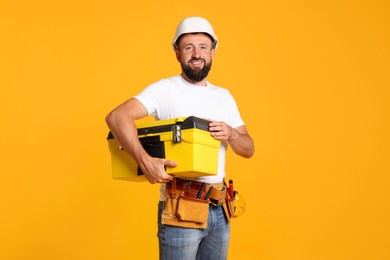 Photo of Professional repairman with tool box on orange background