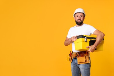 Photo of Professional repairman with tool box on orange background, space for text