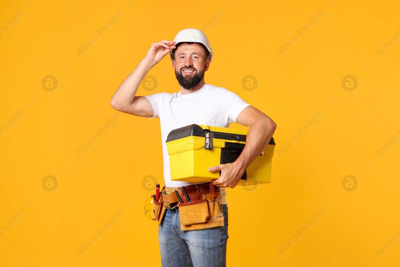 Professional repairman with tool box on orange background Photo of Professional repairman with tool box on orange background