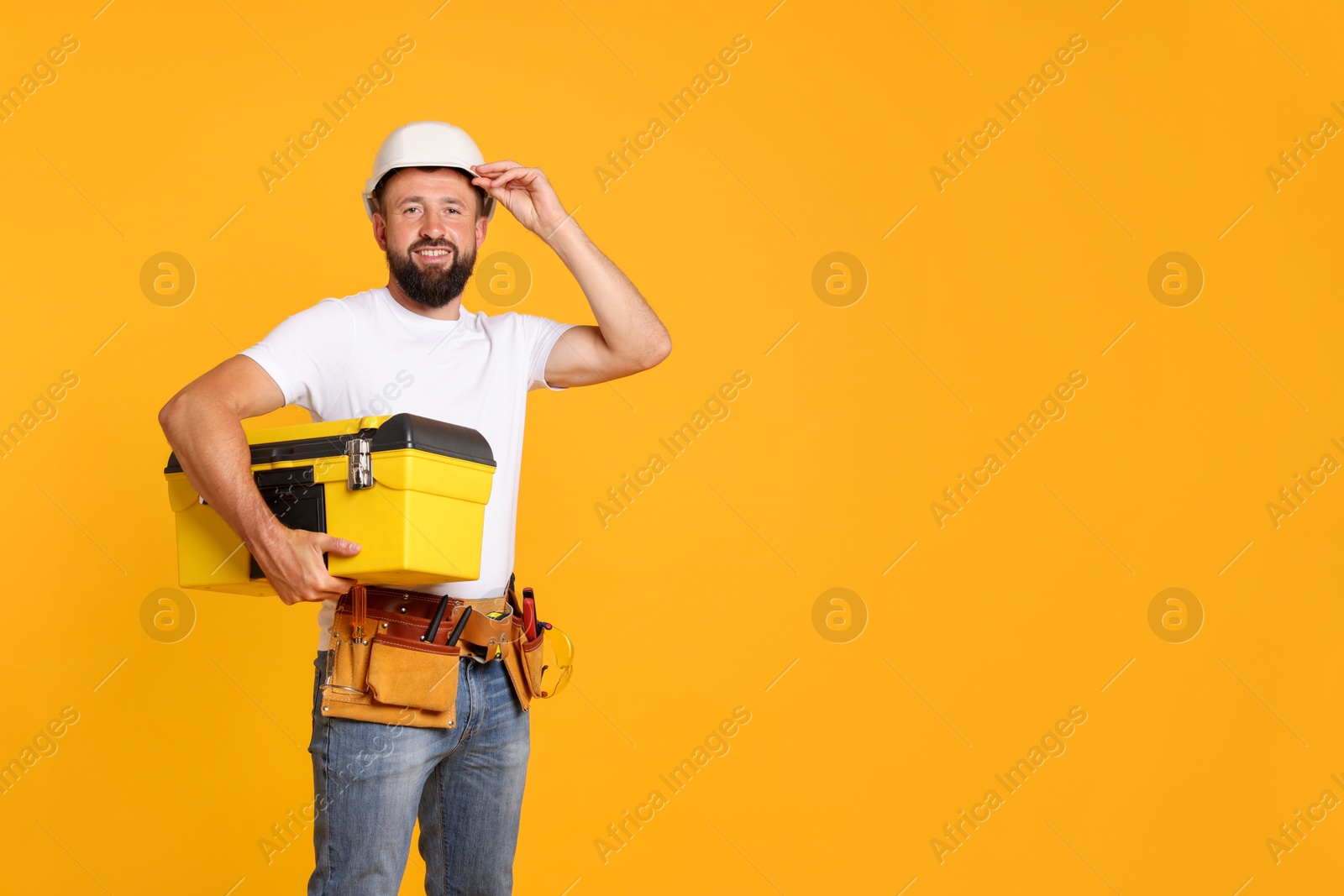 Professional repairman with tool box on orange background, space for text Photo of Professional repairman with tool box on orange background, space for text