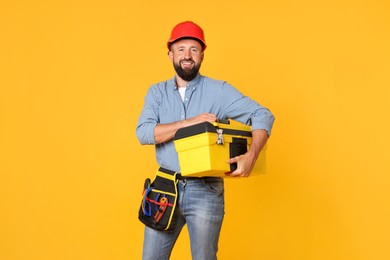 Photo of Professional repairman with tool box on orange background