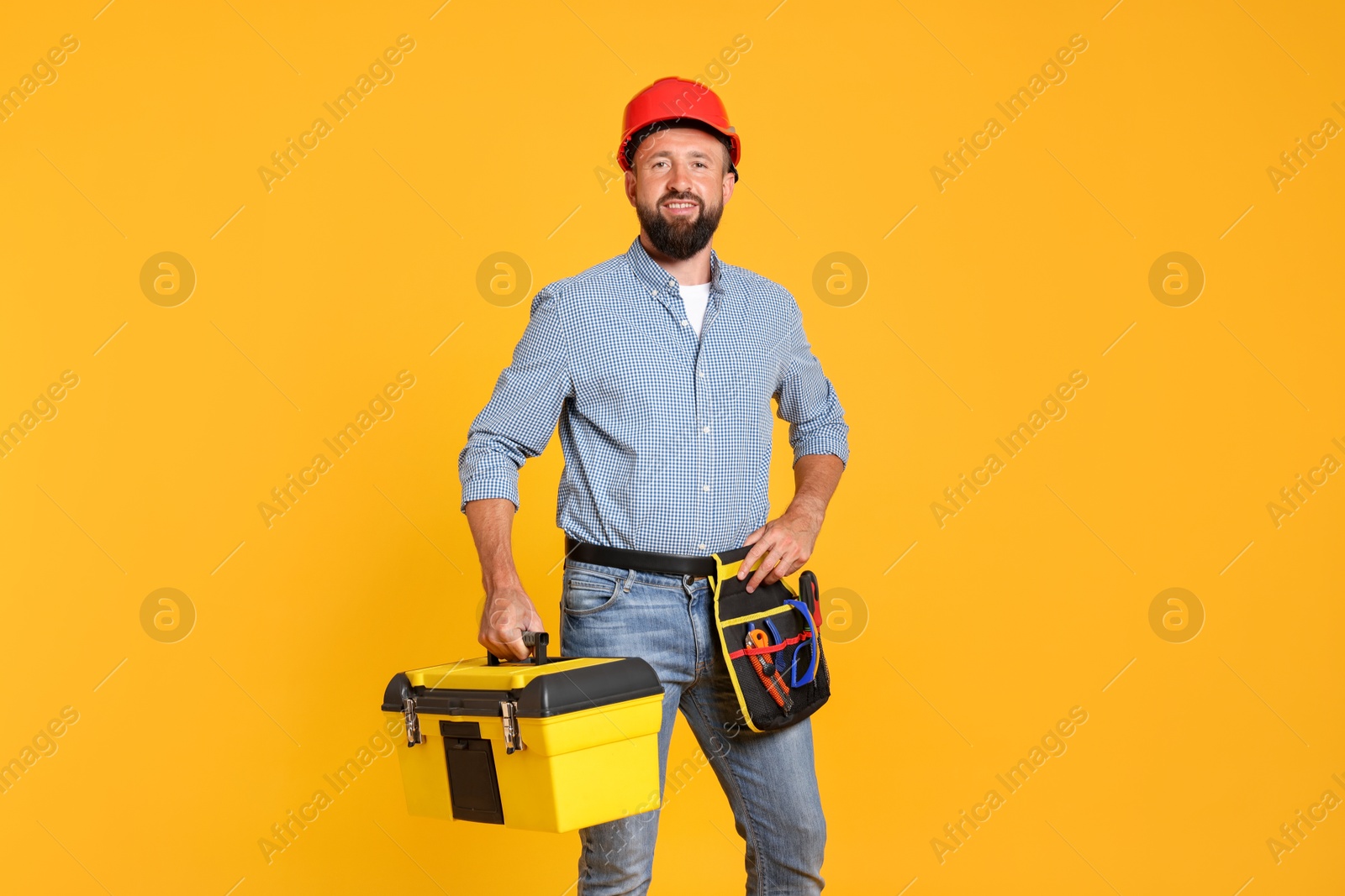 Professional repairman with tool box on orange background Photo of Professional repairman with tool box on orange background