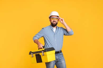 Photo of Professional repairman with tool box on orange background