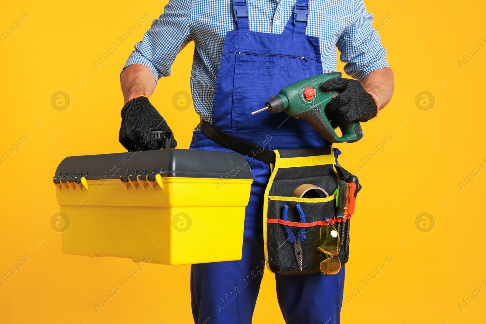 Professional repairman with tool box and electric screwdriver on orange background, closeup Photo of Professional repairman with tool box and electric screwdriver on orange background, closeup