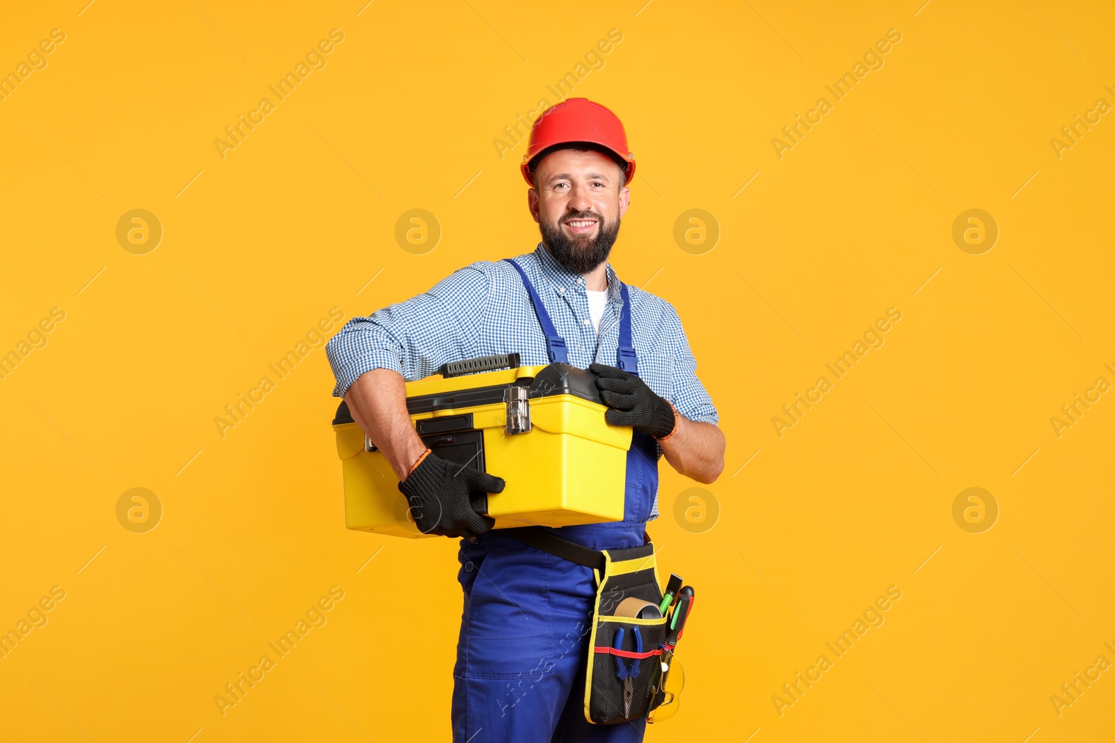 Professional repairman with tool box on orange background Photo of Professional repairman with tool box on orange background
