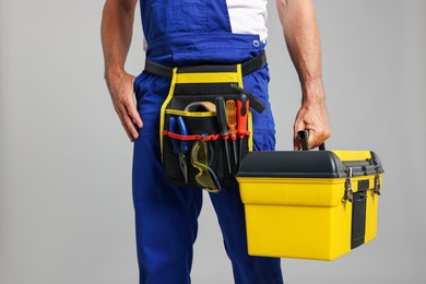 Photo of Professional repairman with tool box on grey background, closeup