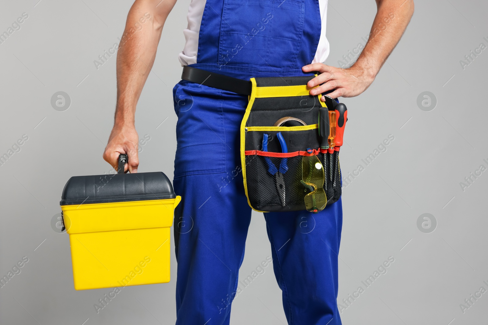 Professional repairman with tool box on grey background, closeup Photo of Professional repairman with tool box on grey background, closeup