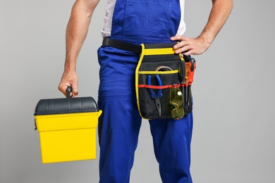 Photo of Professional repairman with tool box on grey background, closeup