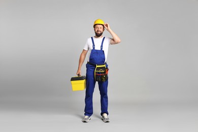 Photo of Professional repairman with tool box on grey background