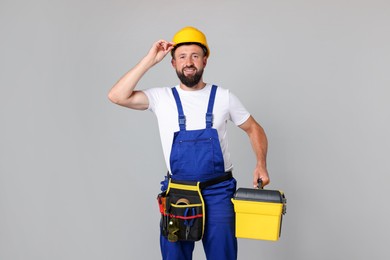 Photo of Professional repairman with tool box on grey background