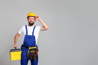 Photo of Professional repairman with tool box on grey background, space for text