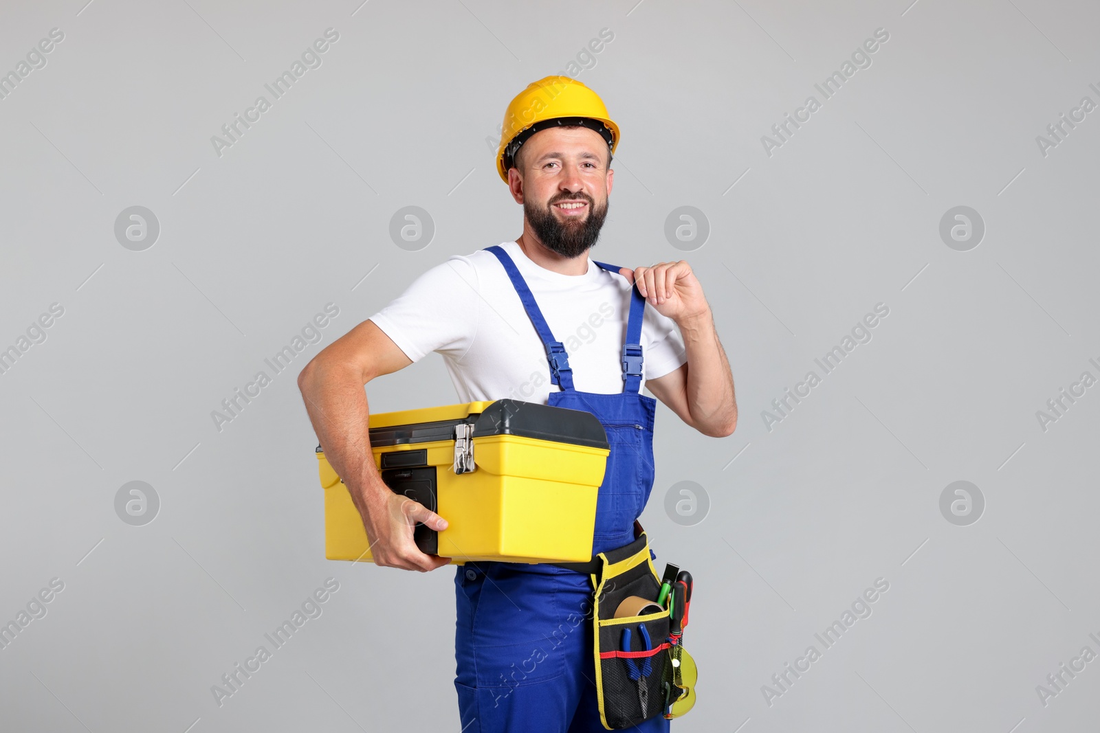 Professional repairman with tool box on grey background Photo of Professional repairman with tool box on grey background