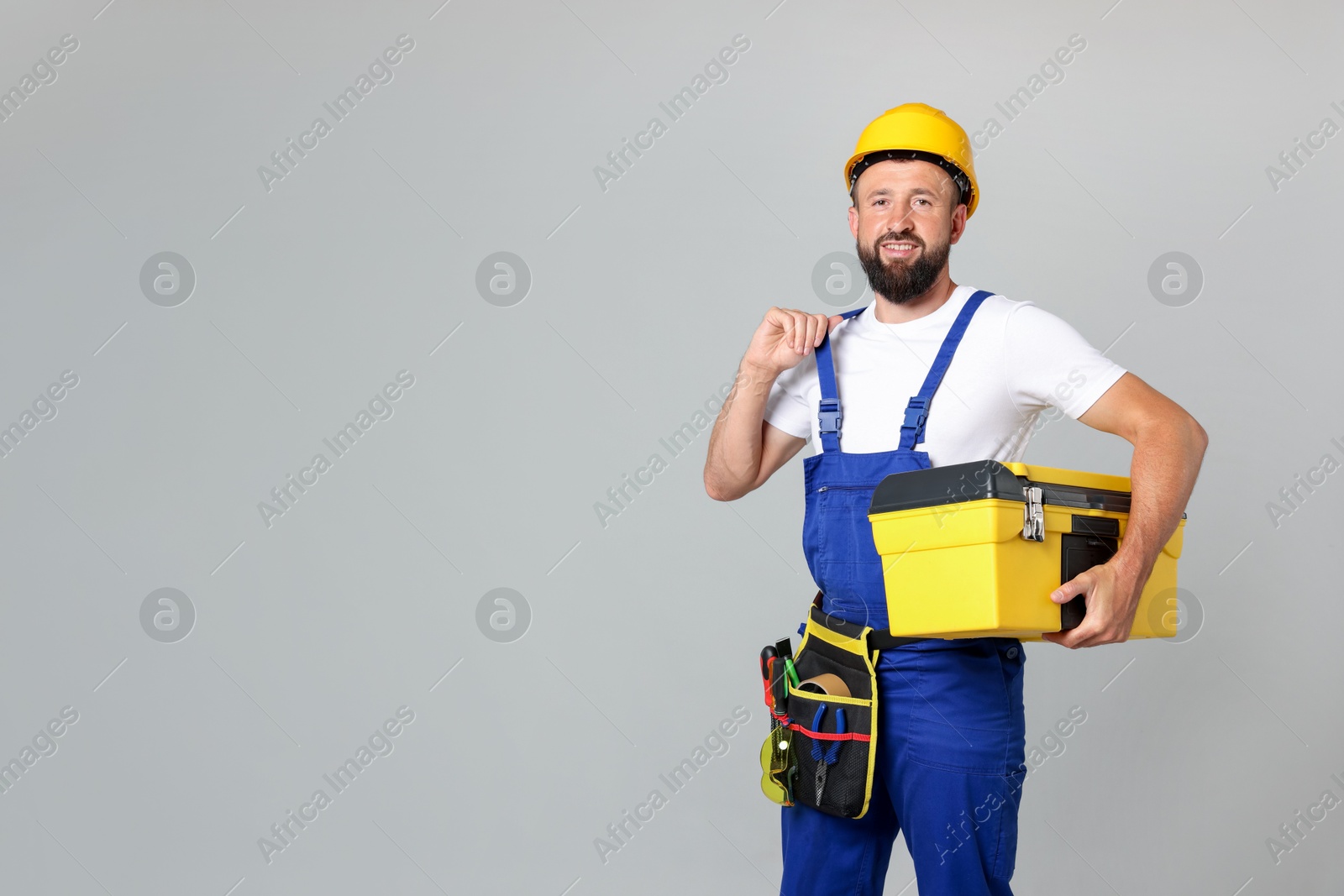 Professional repairman with tool box on grey background, space for text Photo of Professional repairman with tool box on grey background, space for text