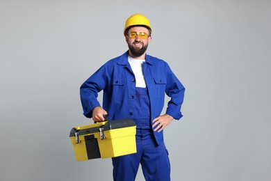 Photo of Professional repairman with tool box on grey background