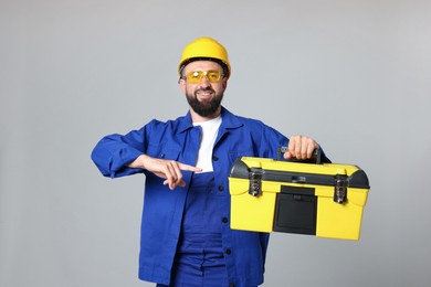 Photo of Professional repairman with tool box on grey background