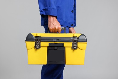 Photo of Professional repairman with tool box on grey background, closeup