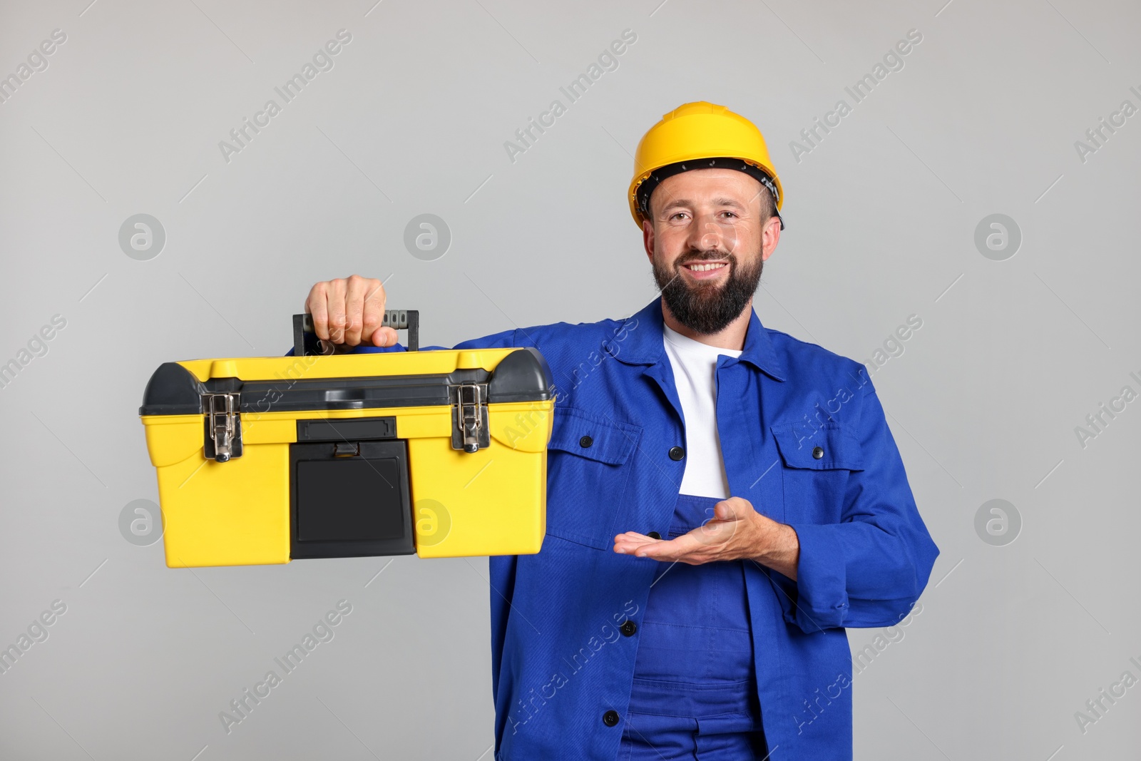 Professional repairman with tool box on grey background Photo of Professional repairman with tool box on grey background