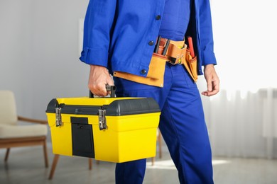 Photo of Professional repairman with tool box indoors, closeup