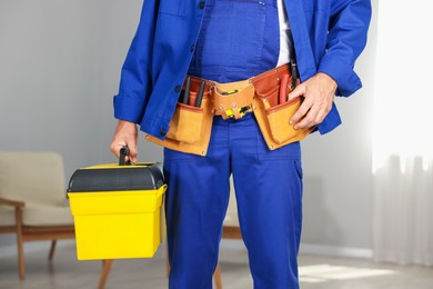 Photo of Professional repairman with tool box indoors, closeup