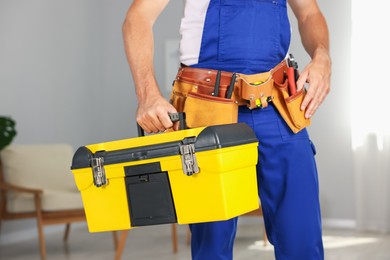 Photo of Professional repairman with tool box indoors, closeup