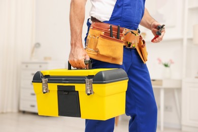 Photo of Professional repairman with tool box indoors, closeup