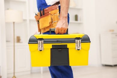 Photo of Professional repairman with tool box indoors, closeup