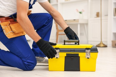 Photo of Professional repairman with tool box indoors, closeup