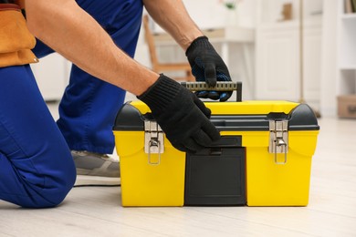 Photo of Professional repairman with tool box indoors, closeup